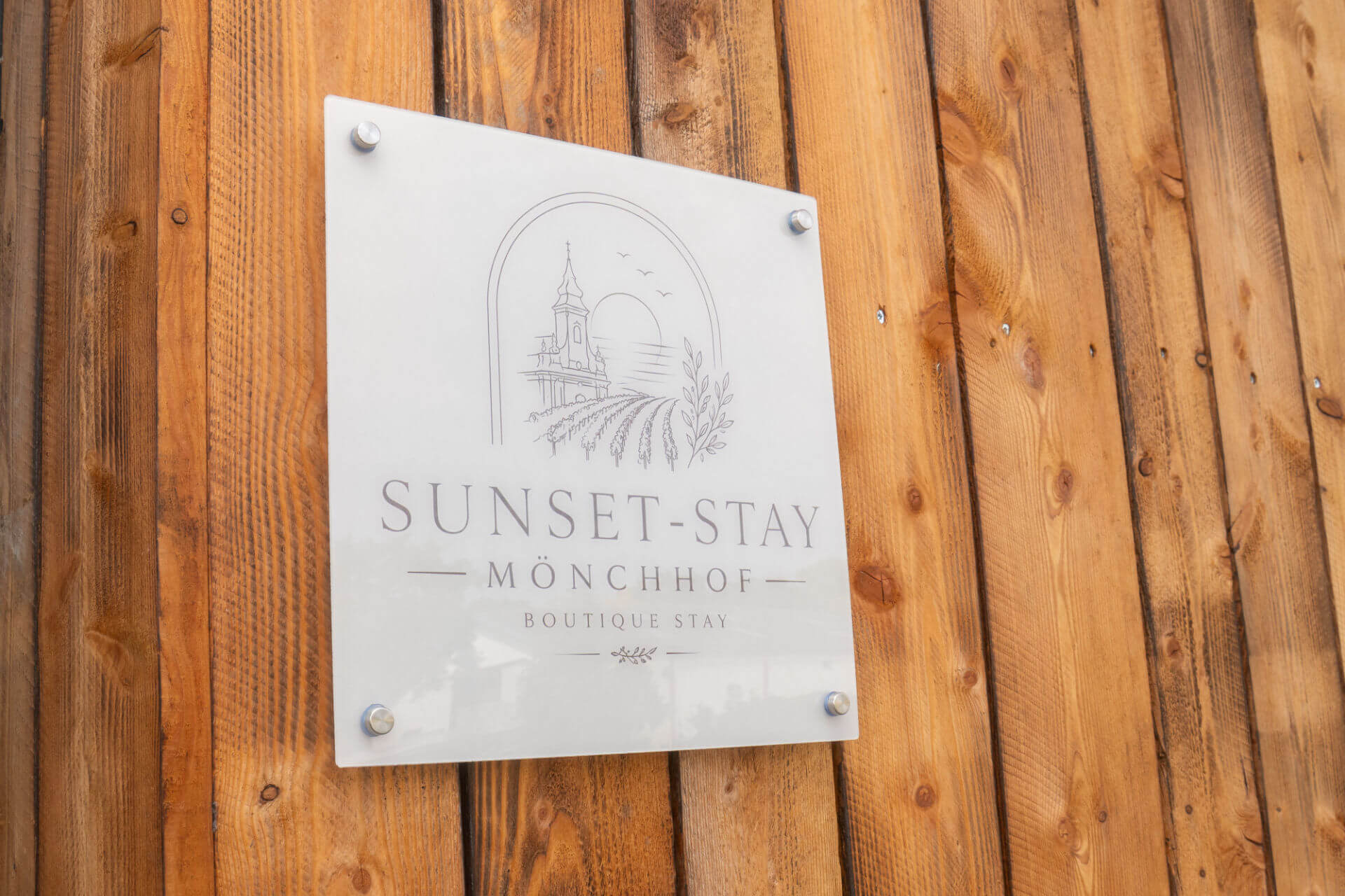 Sunset-Stay Mönchhof Schild an der Holzfassade