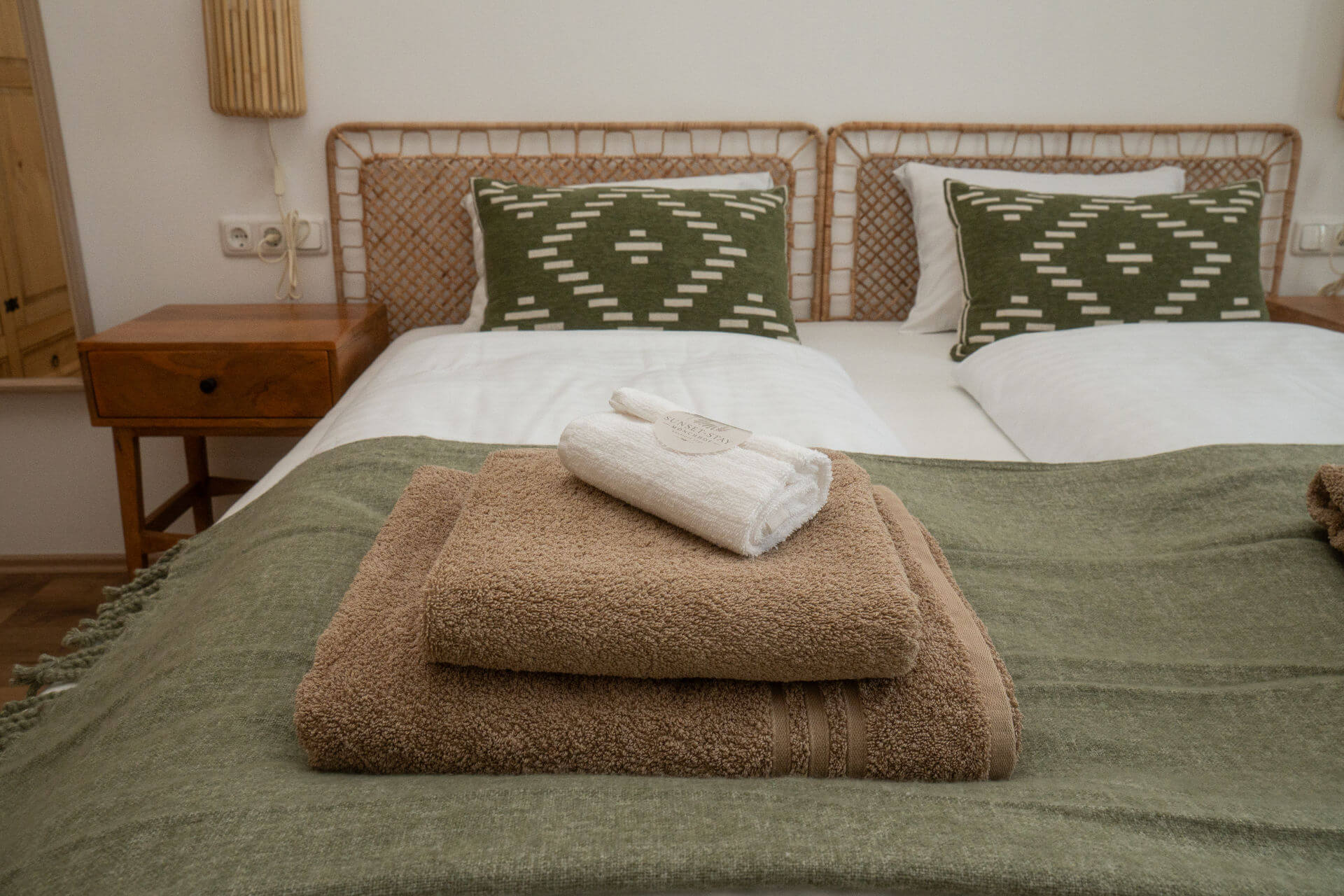Bett mit grünen Kissen und frischen Handtüchern